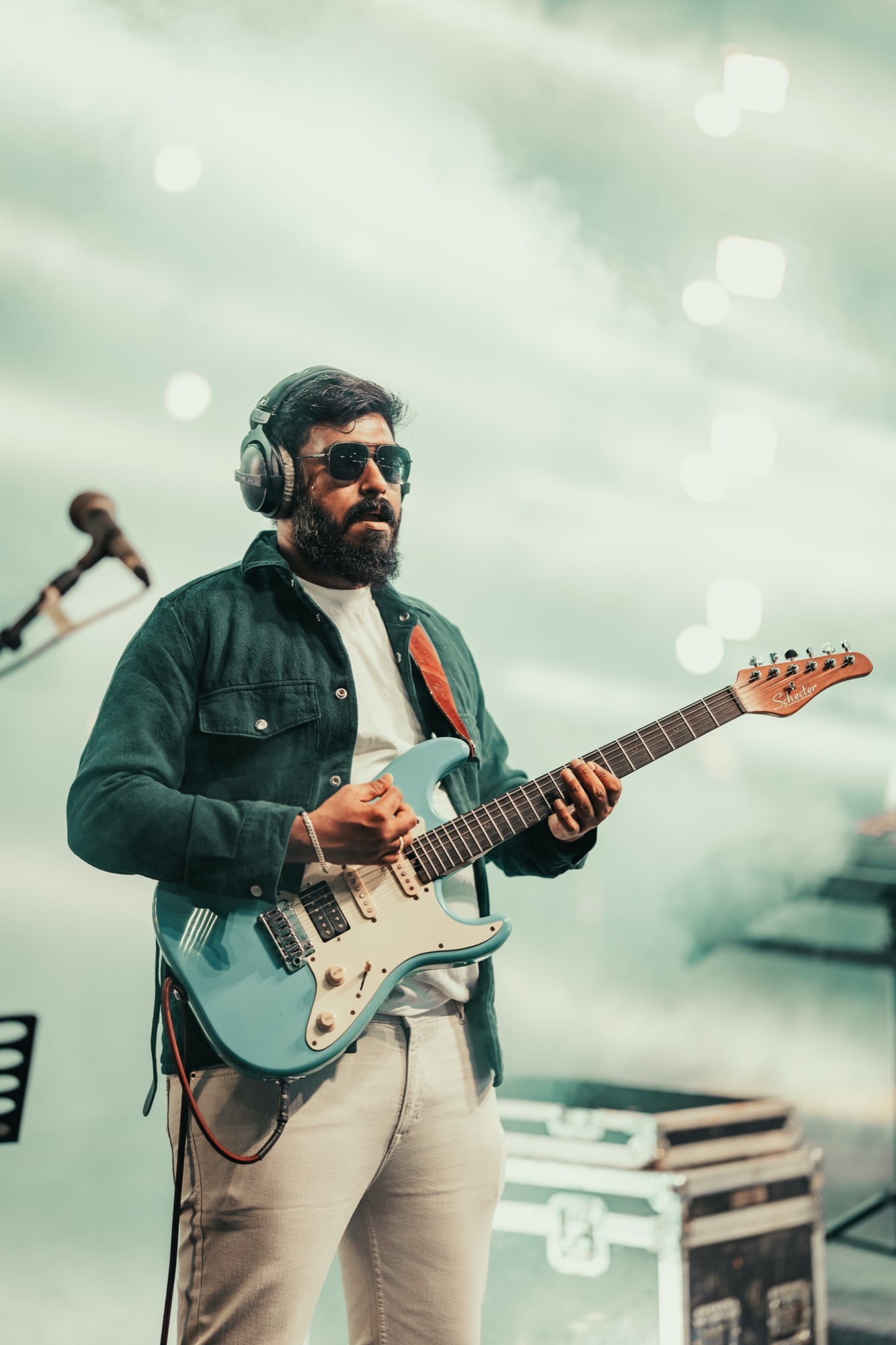 Sanjay playing a light-blue electric guitar on stage