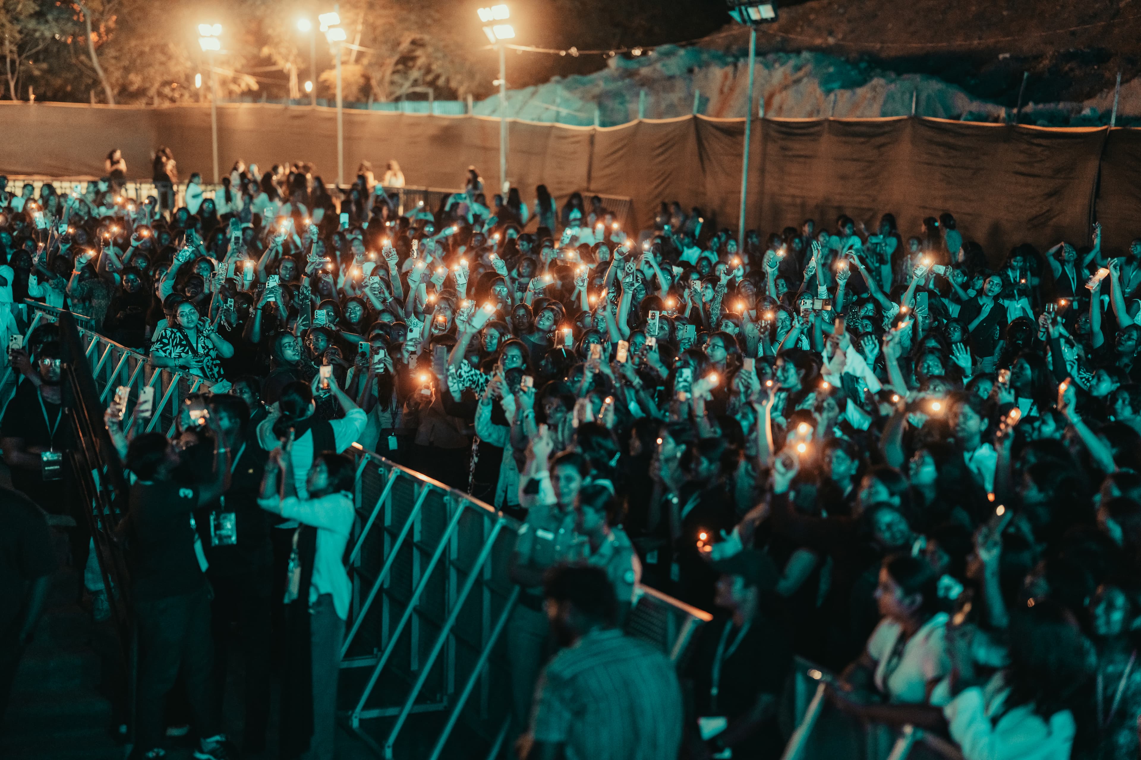 A packed crowd with hands raised in front of a lit stage